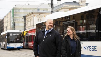 Kaksi bussikuskia seisoo jalkakäytävällä Hämeenkadulla kulkevan Nysse-bussin edessä.