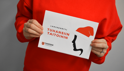 Kädet pitelevät työväenopiston kurssilahjakorttia.