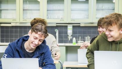 Neljä iloista nuorta miestä pulpettien äärellä.