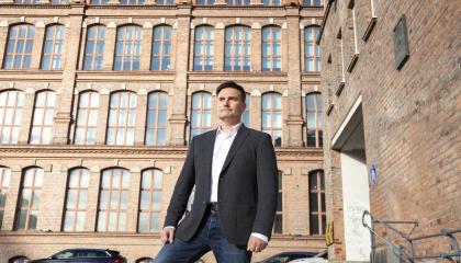 Henkilö seisoo Frenckellin ja Finlaysonin Siperia-rakennuksen välisellä aukiolla vieressään ja takanaan punatiilisiä rakennuksia.