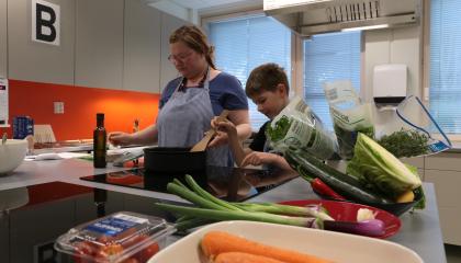 Aikuinen ja lapsi valmistavat kasvisruokaa kotitalousluokan keittiössä.