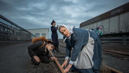 Rautatie-näytelmän hahmot ihmettelevät junaraiteita.