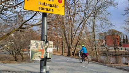 Etualalla pyöräilyn jatkuvuusopaste, taaempana pyöräilijä pyörätiellä.