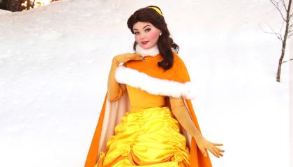 Prinsessa keltaisessa juhlamekossa ja karvaviitassa, kuvattu talvisessa maisemassa.