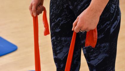 Henkilö pitää kiinni jumppakuminauhasta ja vetää sitä lattialta.