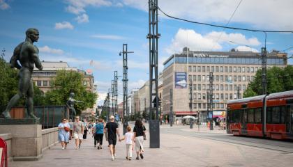 Ihmisiä kävelee Hämeensiltaa pitkin kesäpäivänä, vieressä ajaa ratikka.