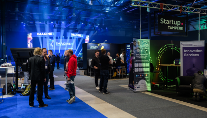 Ihmisiä seisoo tapahtuman messuosastolla.