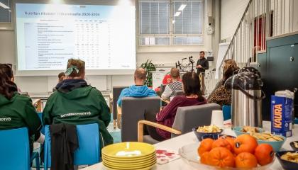 Yleisö istuu selin kameraan ja kuuntelevat luentoa.