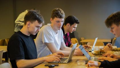 Ryhmä lukio-opiskelijoita opiskelee pöydän ympärillä.