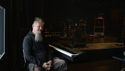 Parrakas henkilö istuu koskettimien edessä tummassa huonessa.