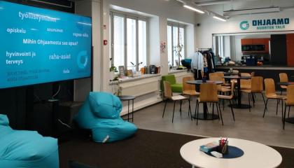 Aula, jossa on pöytiä ja tuoleja sekä kaksi sinistä säkkituolia.