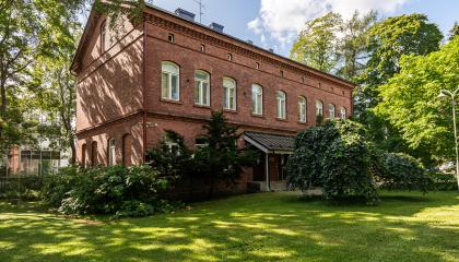 Hatanpään kartanon konttorirakennuksen punatiilinen julkisivu ja piha-aluetta.