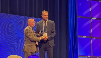 Mies ojentaa palkintoa toiselle miehelle palkintogaalan lavalla.