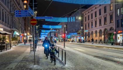 Vanhempi ja lapsi pyöräilevät Hämeenkadulla pimeään aikaan.