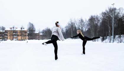 Kaksi tyttöä luistelee ulkokentällä.