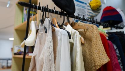 Vaaterekki, jossa roikkuu paitoja. Rekin päällä on pipoja. Takana on hylly.