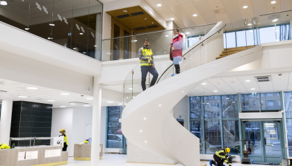 Kaksi henkilöä seisoo korkean aulatilan kaarevissa portaissa.