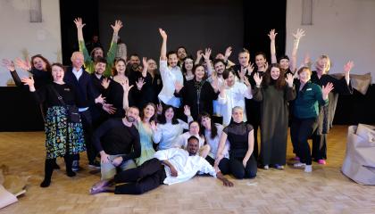 Iloisia ihmisiä poseeraa kameralla ryhmänä.