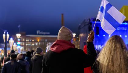 Ihmisiä ilta-aikaan talvisella Keskustorilla, etualalla suomenlippua kädessään pitävä henkilö. Taustalla Finlaysonin rakennus.