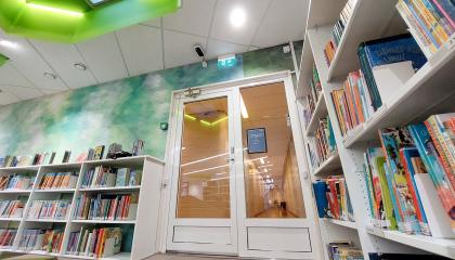 Musta-valkoinen kävijälaskuri kirjaston lasiovien oviaukon yläpuolella.