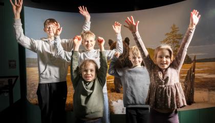 Lapset hurraavat luonnontieteellisessä museossa kädet ylhäällä.