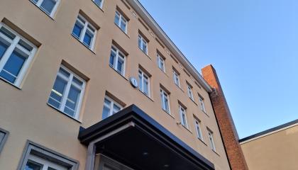 Seinä, jossa on runsaasti ikkunoita ja sisäänkäynnin katos.