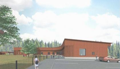 Suunnittelukuva vaaleanruskeasta puupintaisesta päiväkotirakennuksesta. kesämaisemassa.