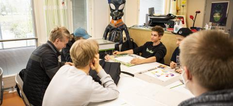 Opiskelijoita pöydän ääressä kuvistunnilla.