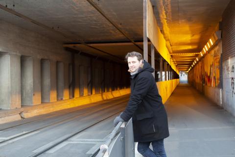 Väänänen nojaa kaiteeseen rautatieaseman alikululla ja katsoo kameraan hymyillen.