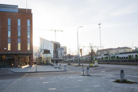 Aamuaurinko paistaa rakennuksen takaa. Kuvassa Tampereen katua.