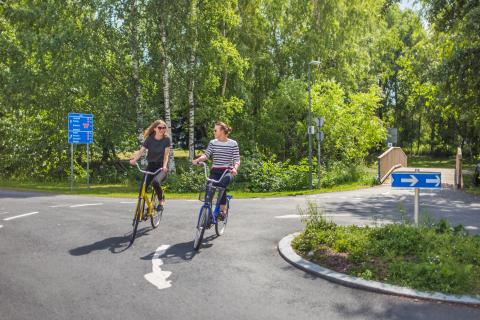 kaksi henkilöä pyöräilevät kesäsäässä.