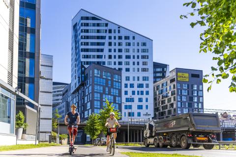 A couple cycling and scooting near Nokia Arena.