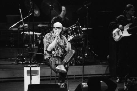 Juice istuu tuolilla ja laulaa mikrofoniin Tampere-talon lavalla.