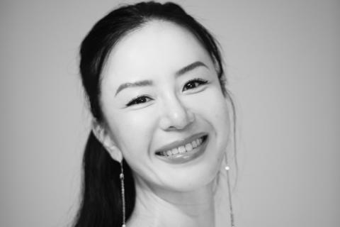 Nuoren naisen kasvokuva. Tummat, pitkät hiukset. Korvissa pitkät ja riippuvat korvakorut. 