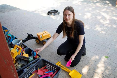 Henkilö siivoaa lasten leluja laatikkoon.