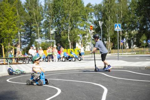 Children’s traffic park a child driving a moped and another child with a kickboard.