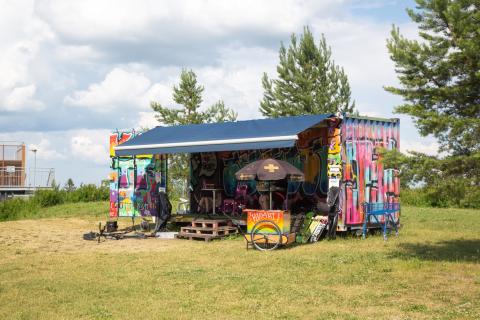 Graffitelilla kotisteltu työmaakontti kesäisessä skeittipuistossa.