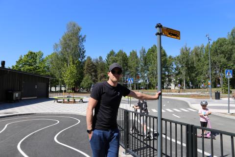 Henkilö mustassa t-paidassa nojaa bussipysäkki kylttiin uudistetussa liikennepuistossa.