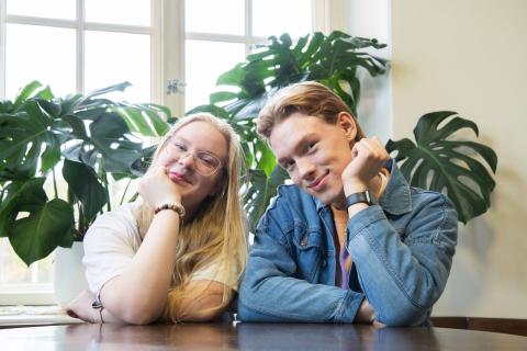 Venla ja Oliver sit at a table and smile to the camera.