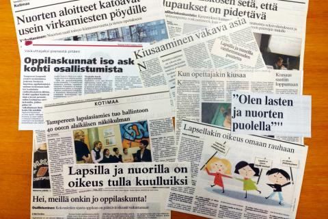 Pöydälle on levitetty lehtileikkeitä, joissa kerrotaan lapsiasiamiehestä tai lasten ja nuorten osallisuudesta.