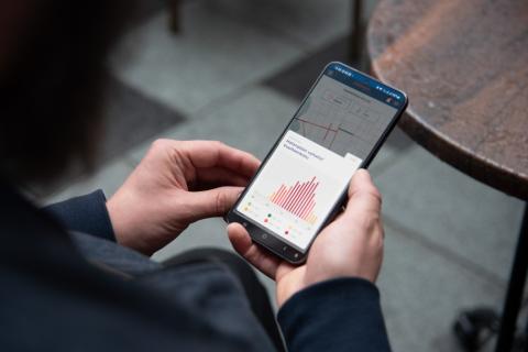 Kädessä oleva kännykkä, josta näkyy Pulssi-sovellus. 