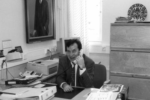 Henkilö istuu vanhassa valokuvassa työhuoneessaan ja pitää puhelinta korvallaan.