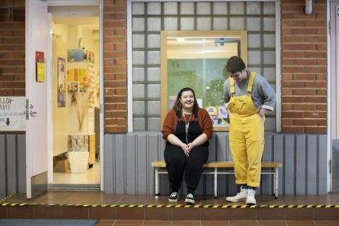 Kaksi kouluvalmentajaa seinän vieressä juttelevat keskenään.