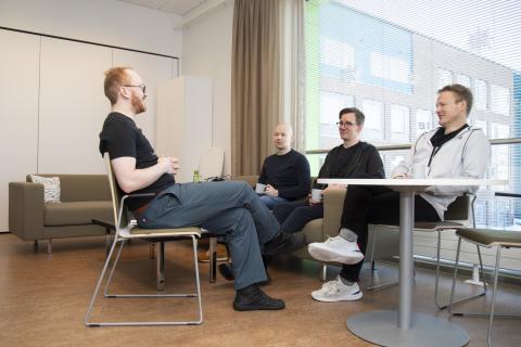 Neljä miestä istumassa huoneessa.