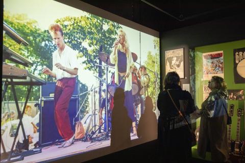 Kuva Vapriikin Manserock-näyttelystä, jossa ihmisiä katsomassa näyttelyssä esillä olevia kuvia.