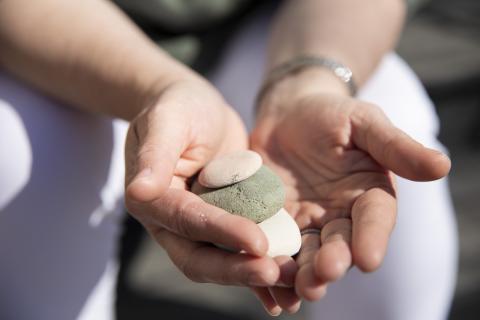 Avoinna olevat kämmenet, jotka pitelevät pieniä kiviä.