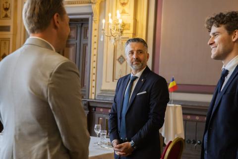 Kolme henkilöä seisoo, keskimmäinen katsoo kameraan.