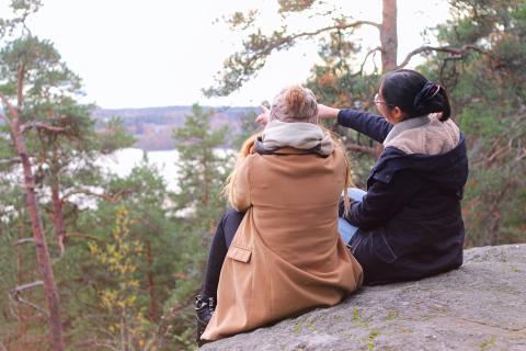 Kaksi nuorta kalliolla metsässä.