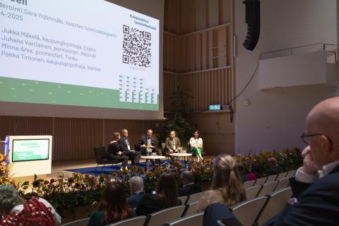 Four city leaders sitting on armchairs during a panel at Urban Nature Forum.