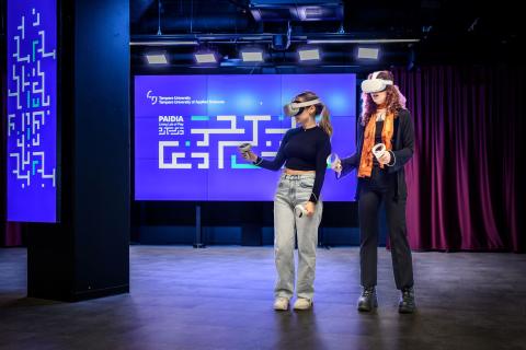 Kaksi nuorta henkilöä VR-lasit päässään ja VR-ohjaimet käsissään.